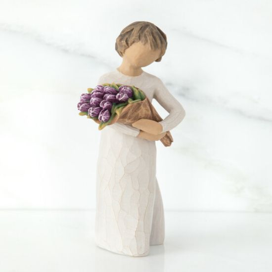 Girl figurine with short brown hair in white dress holding purple flowers